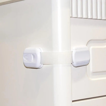 Child safety lock on a white cabinet door.