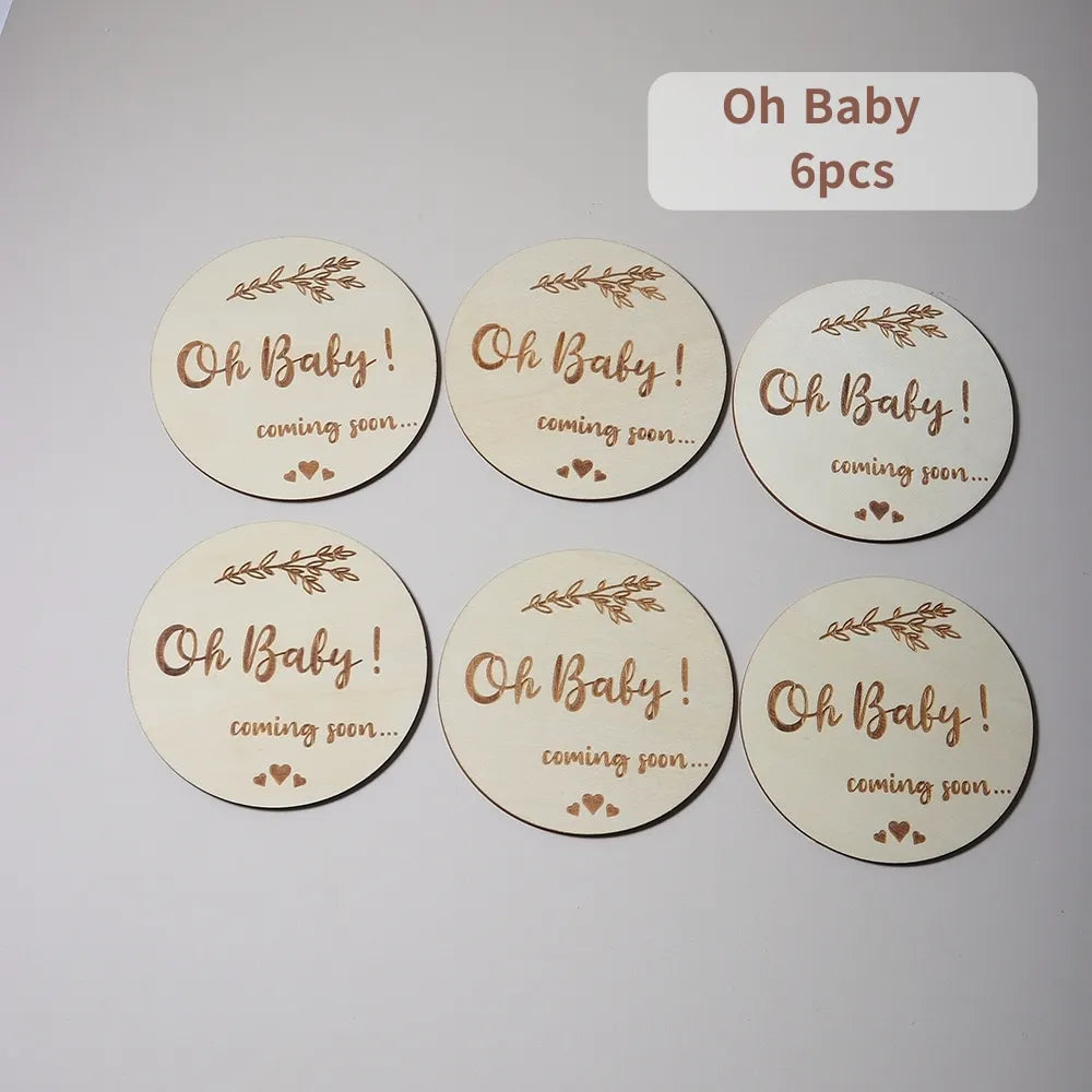 Six wooden discs with Oh Baby! coming soon... text and leaf motifs.