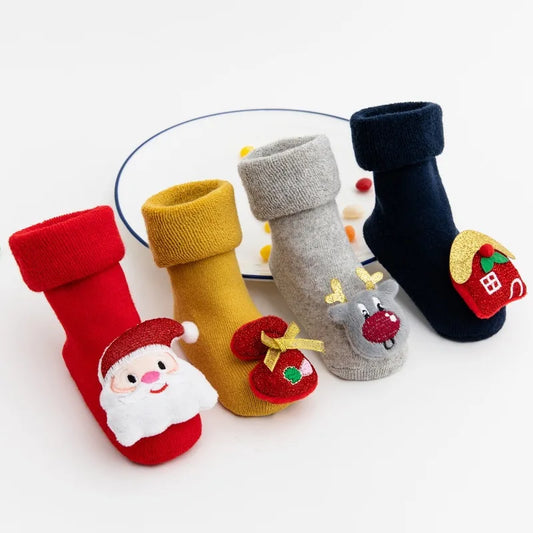 Four Christmas Baby Socks With Cartoon Design In Red, Blue, Yellow, And Grey In A White Background