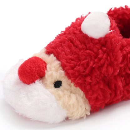 A closeup photo of red baby winter shoes featuring a cheerful Santa Claus face on the front In A White Background