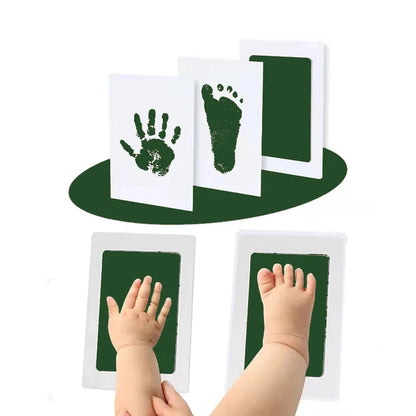 Hand and footprints on paper beside a baby's hand and feet.