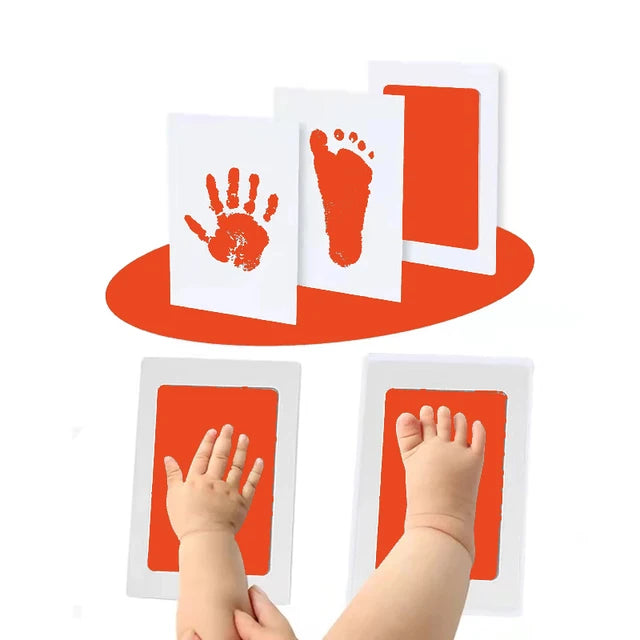 Child's hand and foot with orange paint prints on paper.