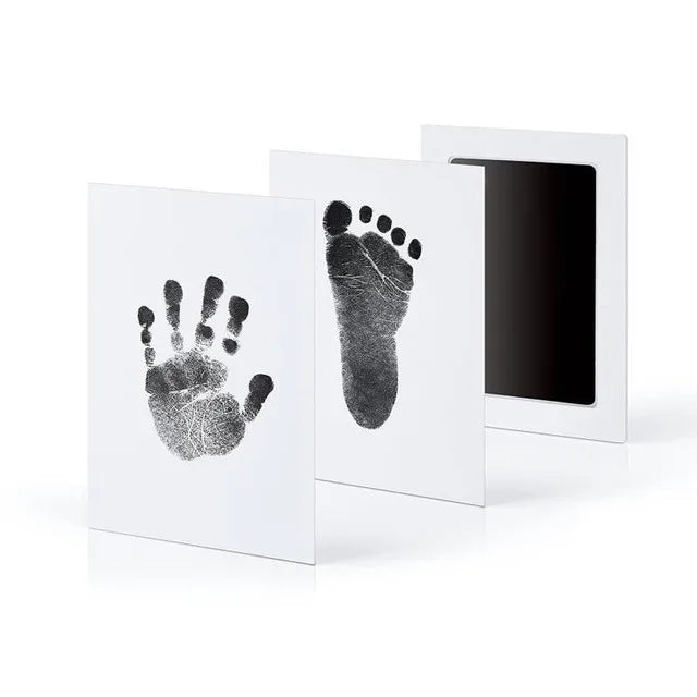 Two framed prints displaying black handprint and footprint on white backgrounds.