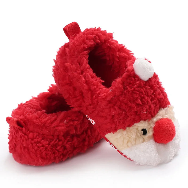 A pair of red baby winter shoes featuring a cheerful Santa Claus face on the front In A White Background