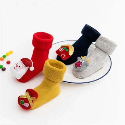 Four Christmas Baby Socks With Cartoon Design In Red, Blue, Yellow, And Grey In A White Background