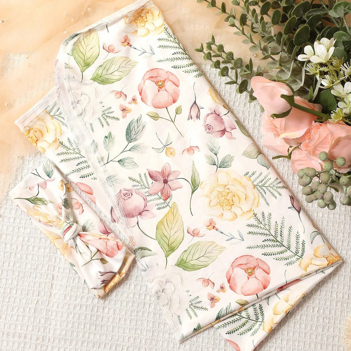 Floral fabric with printed pink and yellow flowers on a light background, alongside greenery.