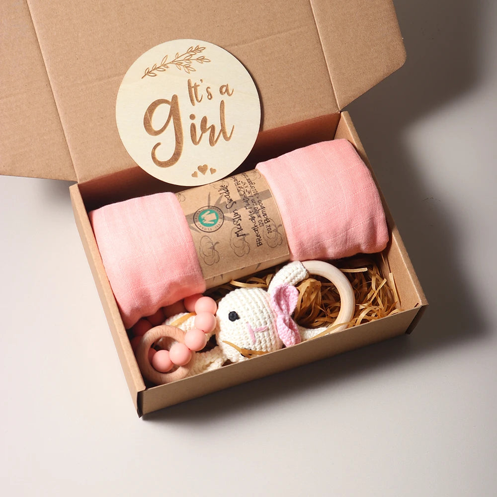 Gift box with It's a Girl label, pink blanket, and crochet bunny toy.