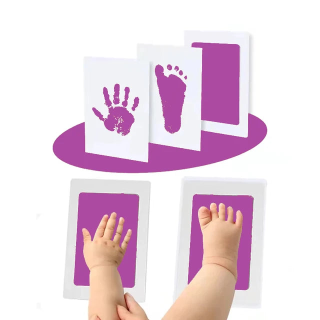 Handprint and footprint art with a child's hand and feet placed on white paper, purple background.