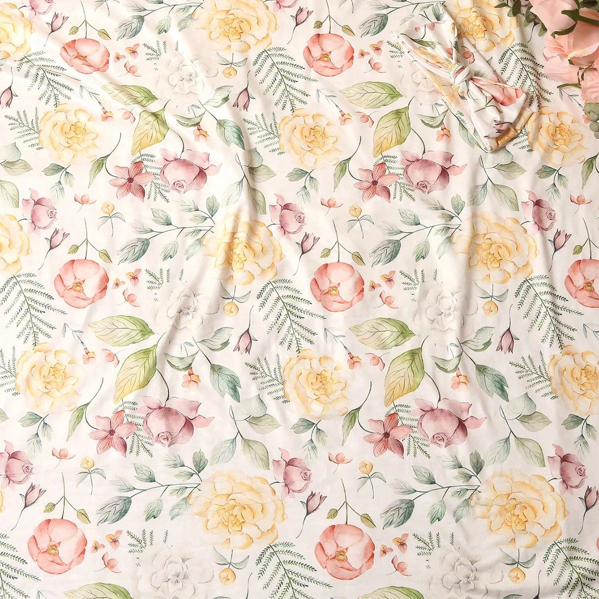 Floral fabric with pink and yellow roses and green leaves.