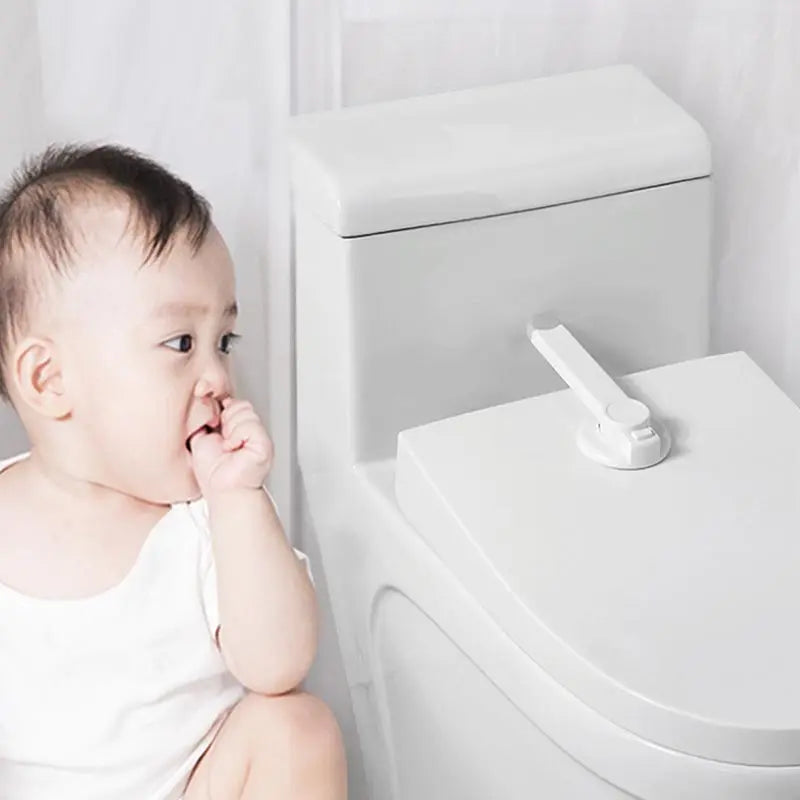 A Child Sitting Beside A White Toilet Bowl With Toilet Lock 