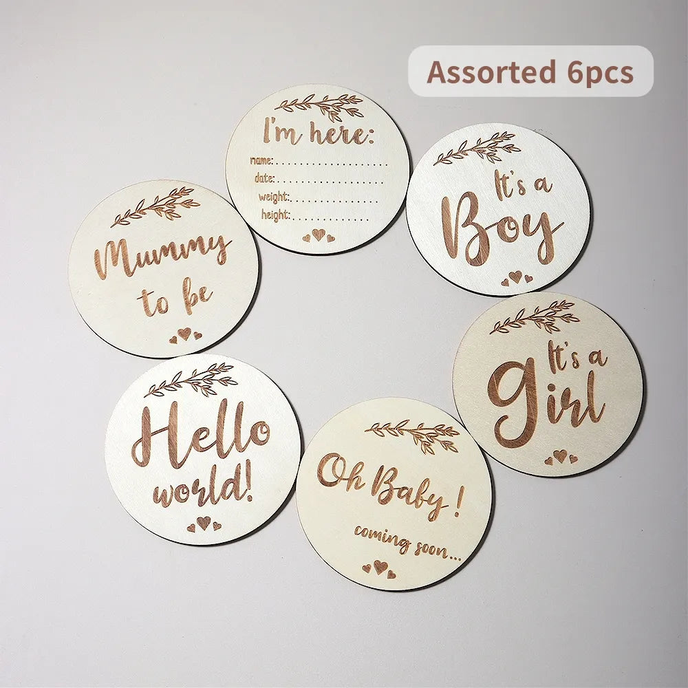 Set of six wooden baby milestone discs with various inscriptions in script.