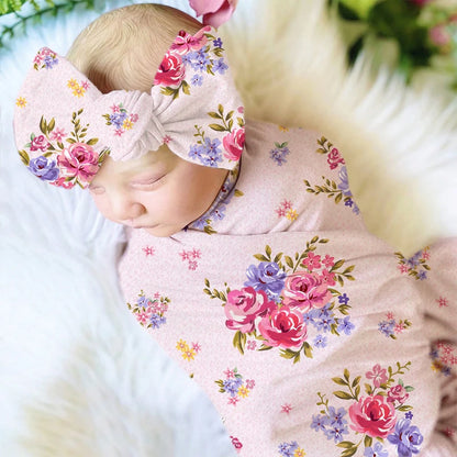 A baby in a floral outfit lying on a soft surface, with head turned away from the camera.