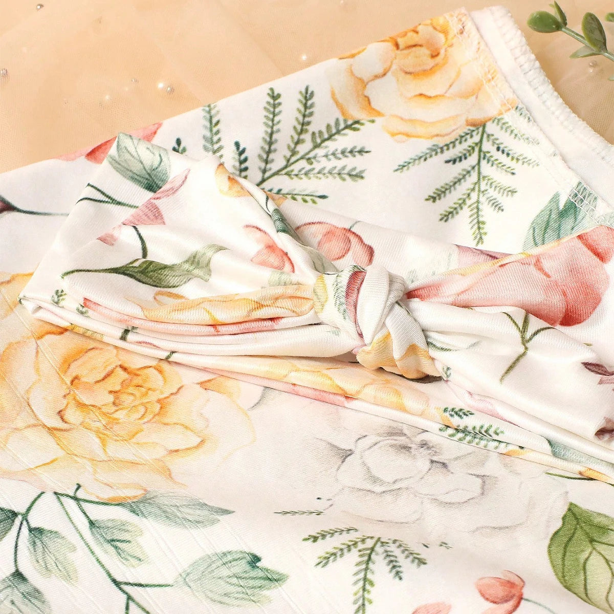 Floral fabric with printed pink and yellow flowers on a light background, alongside greenery.