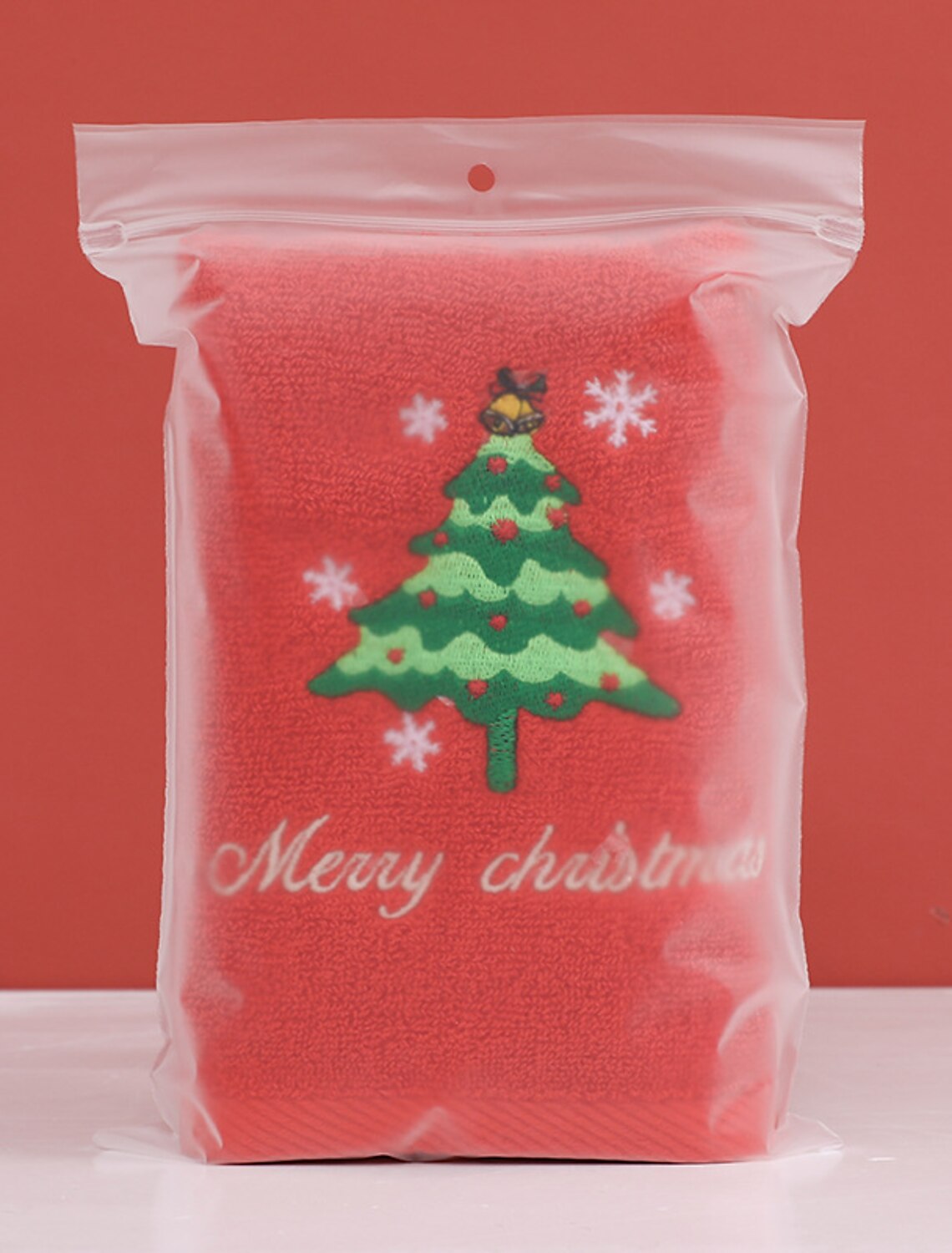 Red Christmas Baby Towel With Embroidered Christmas Tree Design Packed In A Zip Lock Plastic Bag In A Red Background